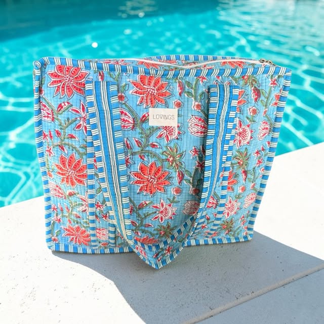 Blauwe handgemaakte Lovings-tas met bloemenprint bij het zwembad